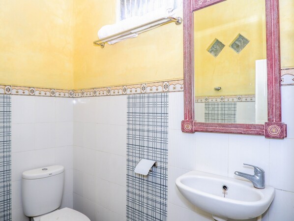 Un baño con inodoro, lavamanos y espejo.
