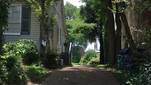 A gravel driveway leading to a house with a front yard and trees. - 2 Melinda’s Garden Apt  (Natchez)
