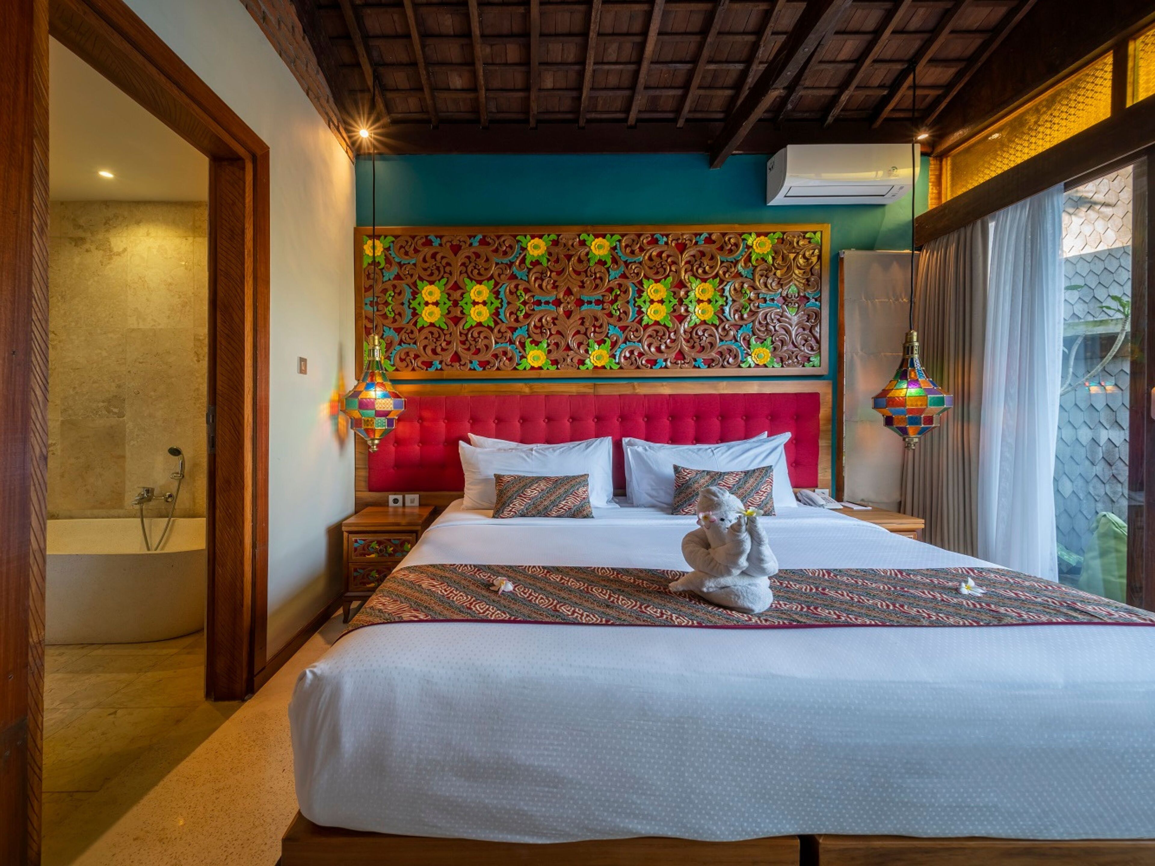 Un dormitorio amplio con una cama grande, un cabecero rojo y un panel decorativo en la pared.