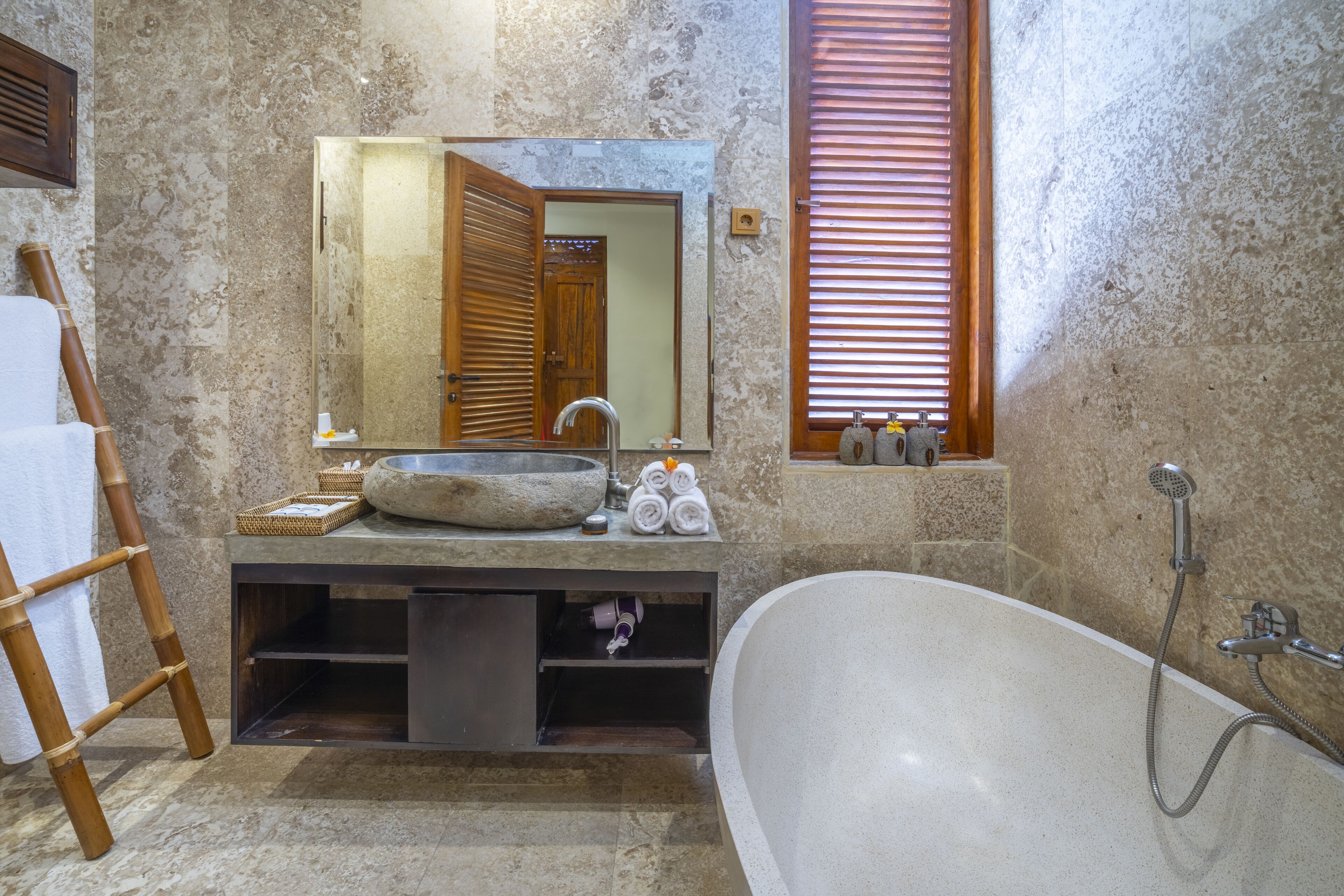 A bathroom with a stone sink, wooden door, and a bathtub.
