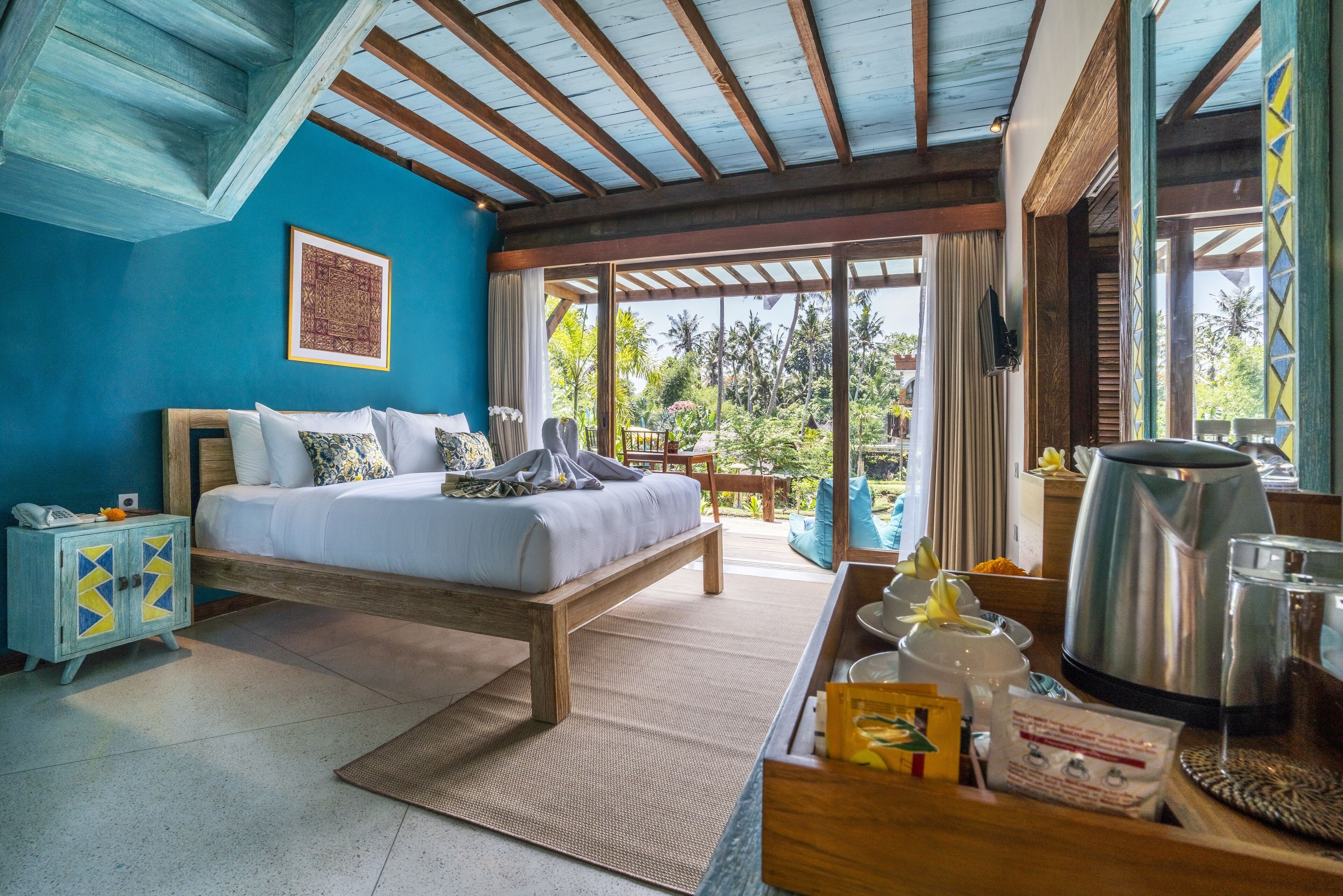 Une chambre à coucher comprenant un lit, une tête de lit en bois, une table de chevet, une table basse et une vue sur l’extérieur.