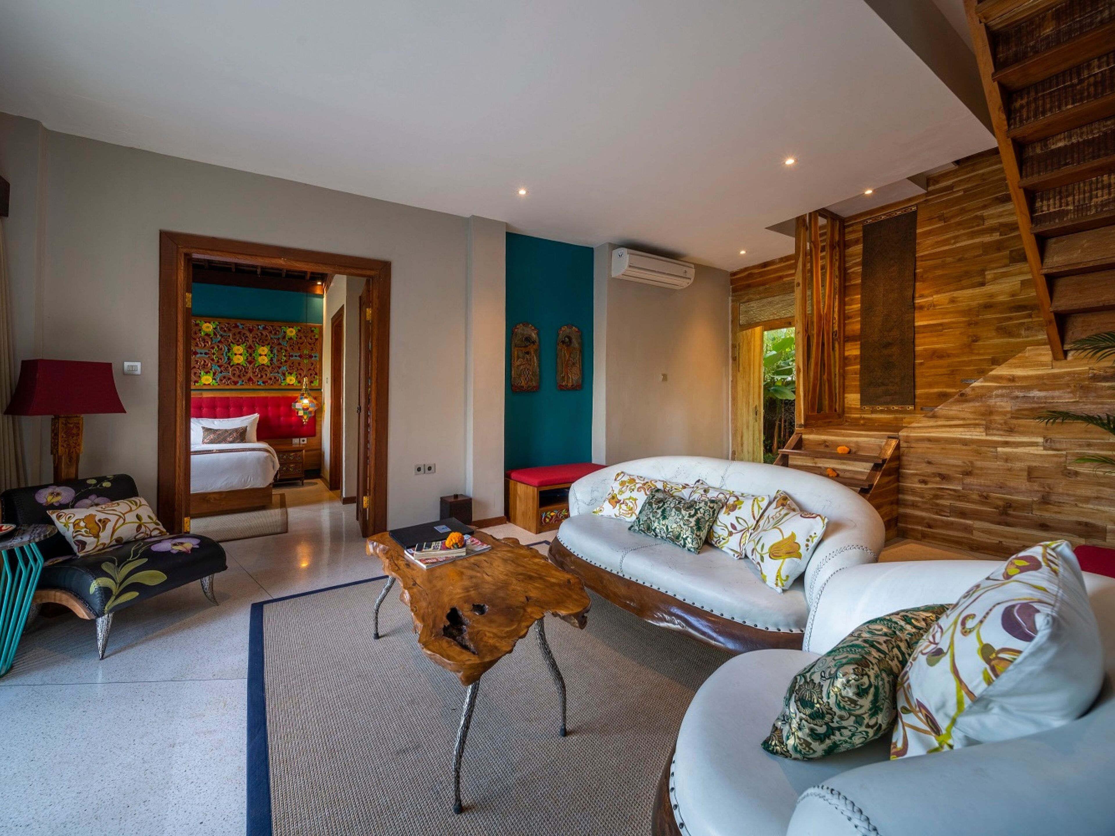 A modern living room with a sofa, a coffee table, and a bed with a red headboard.