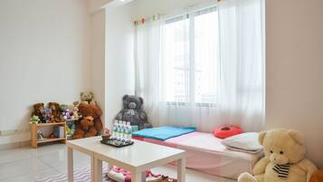 Un dormitorio infantil con una cama, un escritorio y una ventana con cortinas.