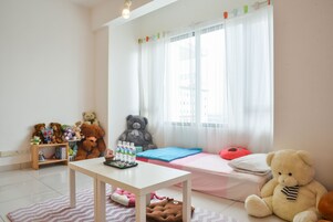Un dormitorio infantil con una cama, un escritorio y una ventana con cortinas.