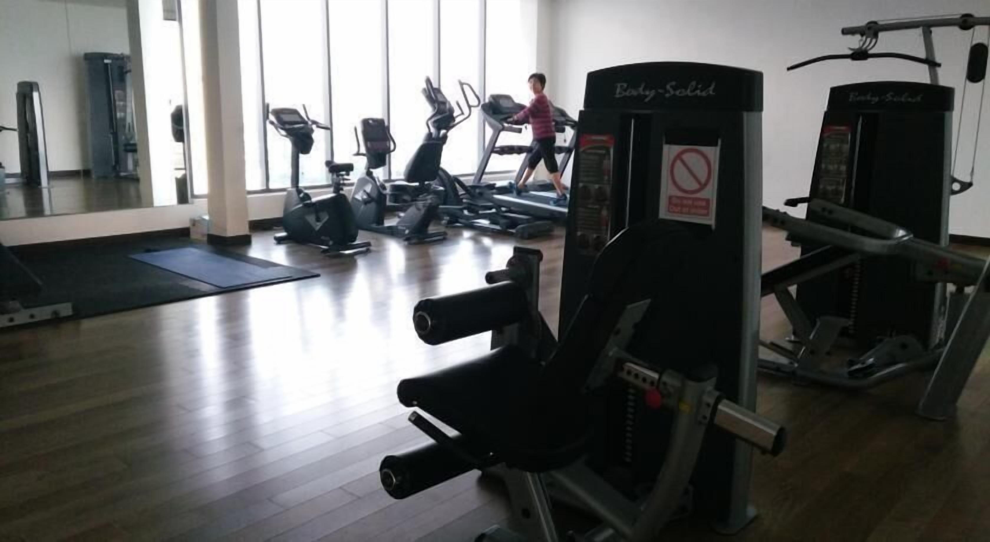 A gym with cardio machines, weight training equipment, and a no smoking sign.