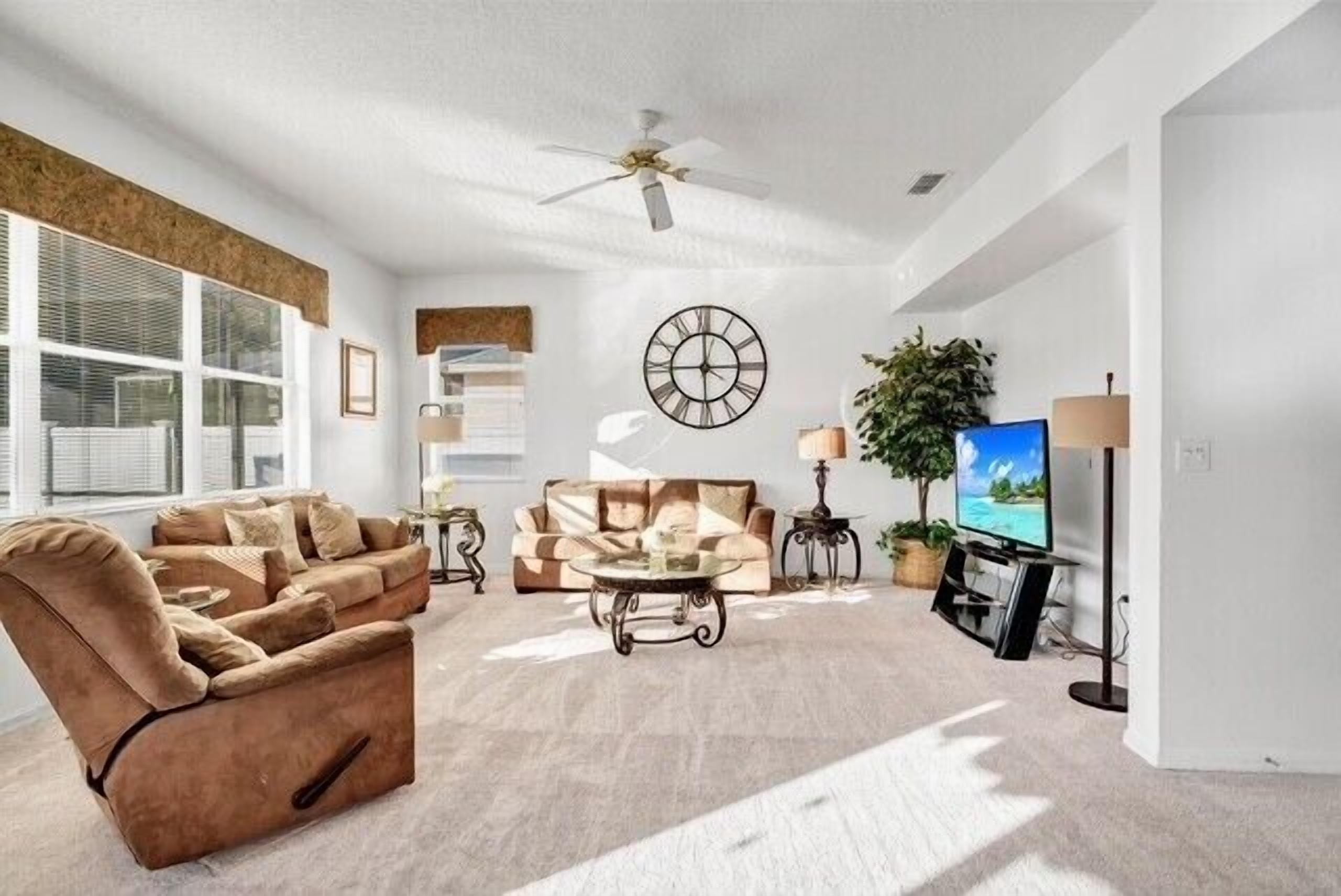 A spacious living room with a sofa, armchair, coffee table, and a television.