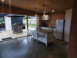 Eine kleine Küche mit einer zentralen Kochinsel, Barhocker, einem Kühlschrank und einem Herd.