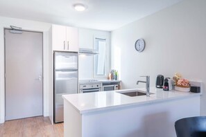 Una cocina moderna con refrigerador, estufa, pileta y un reloj en la pared.