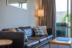 Una sala de estar moderna con un sofá de cuero, una mesita auxiliar, una lámpara y vistas al exterior.