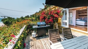 Una terraza al aire libre con una parrilla, asientos y vistas al mar.