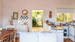 Una cocina compacta con armarios blancos, encimera de madera y ventana con persianas.