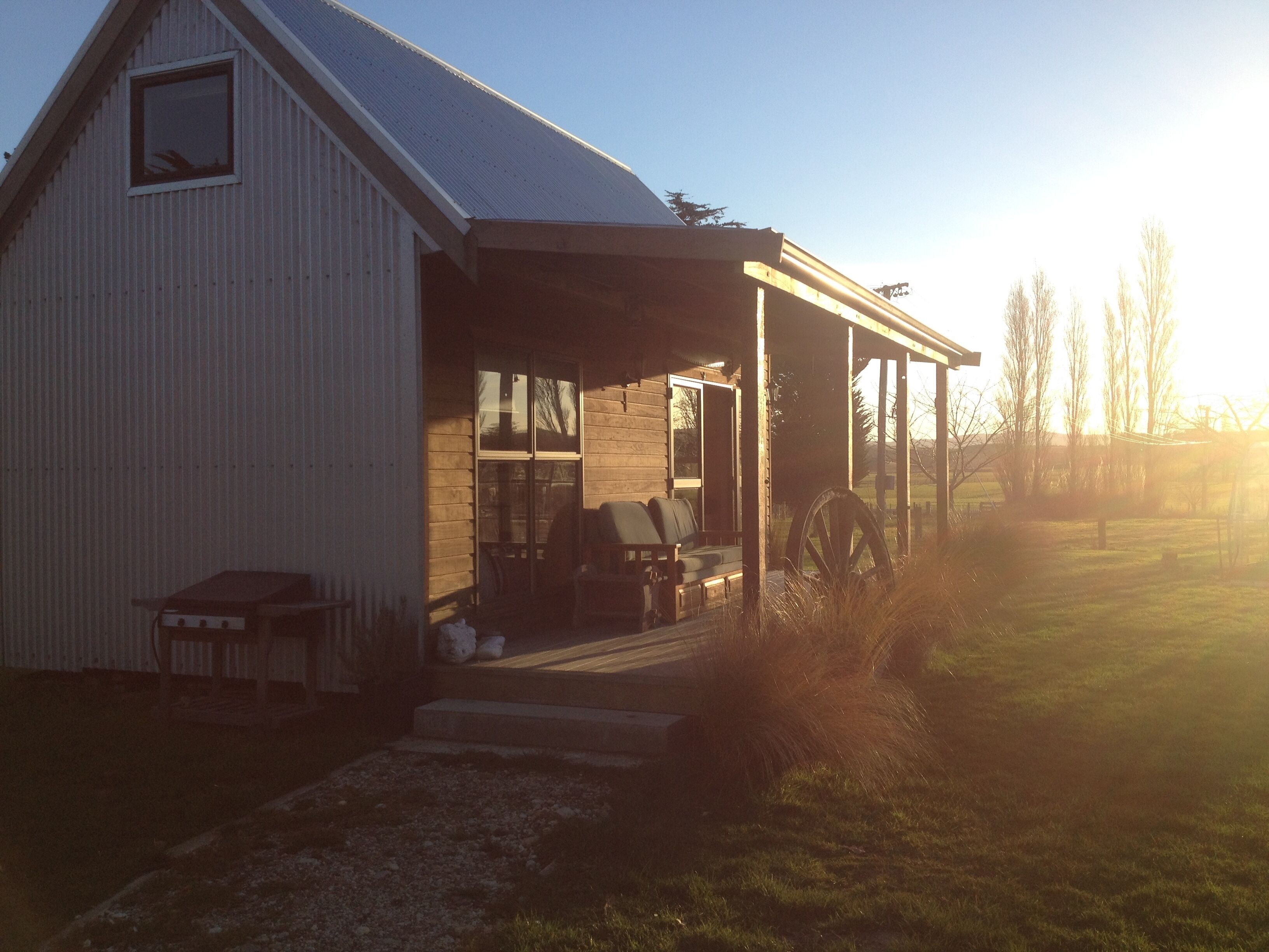 A single-story building with a covered porch, a small table, and a chair outside.