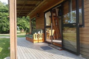 Une terrasse en bois avec une porte-fenêtre coulissante donnant sur une pièce.
