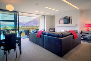 Relax in comfort with a scenic mountain view from the large window, a flat-screen TV, and a cozy sofa.