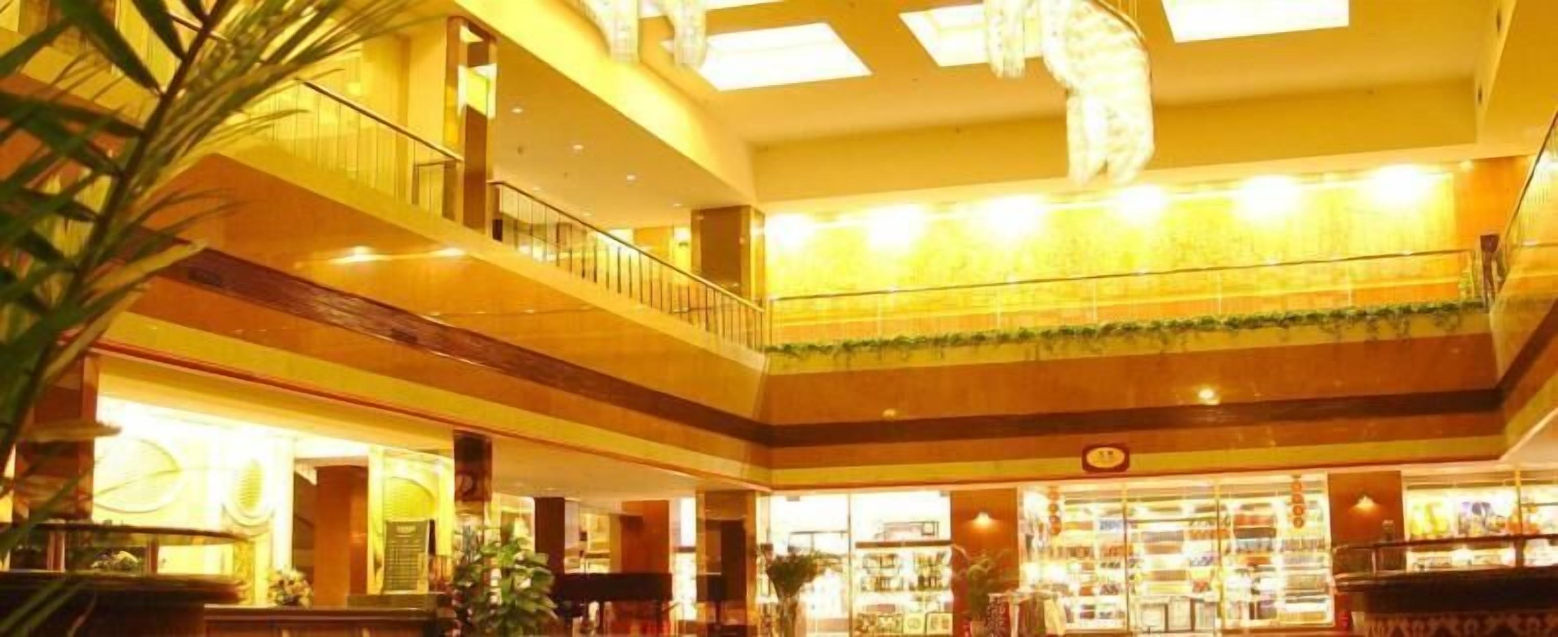 A multi-level atrium with a central staircase, glass railings, and a variety of shops on the ground floor.