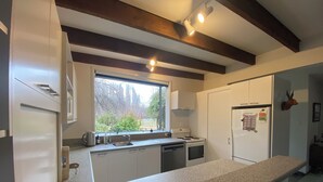 A modern kitchen with granite countertops, white cabinetry, a built-in oven, and a window providing a view of the outdoors.