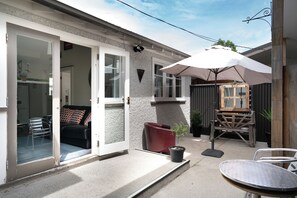 Eine Terrasse mit Tisch, Stühlen, einem Topfpflanzen und einer Holzbank.