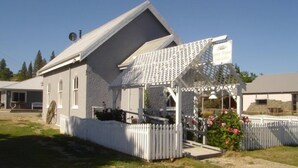 A white building with a sloped roof and a small porch area with a lattice roof. - Lovely overnight double room with en-suite (Alexandra)