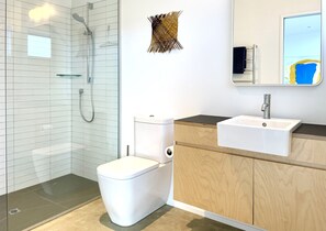 Ein modernes Badezimmer mit Duschkabine aus Glas, einer weißen Toilette, einem Holzwaschtisch mit Waschbecken und einem Spiegel mit Wanddeko.