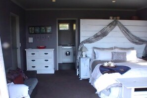 A bedroom with a bed, a dresser, a nightstand, a window, and a door. - Miranda Sea View Apartment (Miranda)