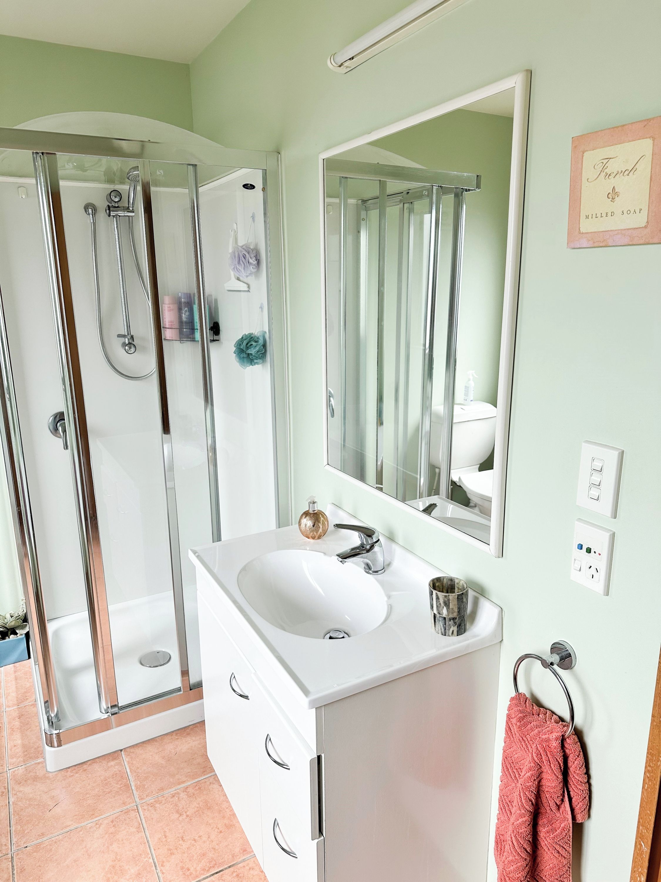 A bathroom with a shower, sink, and mirror.
