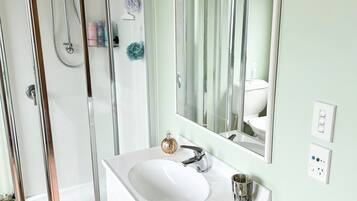 A bathroom with a shower, sink, and mirror.