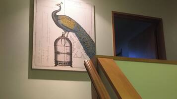 A staircase with a wooden handrail and a wall-mounted picture featuring a peacock and a birdcage.