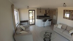 A modern living room with a sofa, a coffee table, and a kitchen area with a bar.