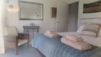 A bedroom with a bed, a chair, a desk, and a door.