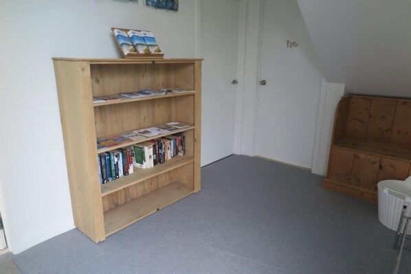 A room with a wooden bookshelf filled with books, a white door, and a wooden cabinet.