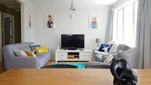 A modern living room with two sofas, a TV, and a wooden table.