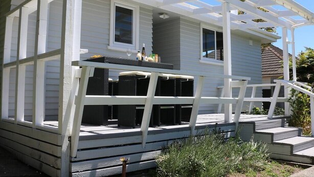 A white house with a covered porch and a small deck.