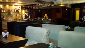 A bar area with a bartender, a brick wall with liquor bottles, and seating with a 'SMOKE ZONE' sign. - Hotel Chennai Gate (Chennai)