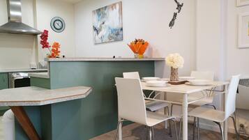 Una cocina moderna con una isla central, sillas blancas y una mesa de comedor.