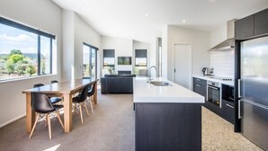 A modern kitchen with a large island, dark cabinetry, and a view through the windows. - Simply Stunning - Wanaka (FREE WI-FI) (Wanaka)