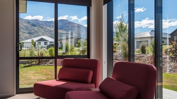 A modern room with large windows offering a view of a mountainous landscape and neighboring houses. - Simply Stunning - Wanaka (FREE WI-FI) (Wanaka)