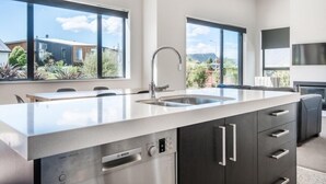 A modern kitchen with a stainless steel Bosch dishwasher, a double sink, and a large window offering a view of the surrounding area. - Simply Stunning - Wanaka (FREE WI-FI) (Wanaka)