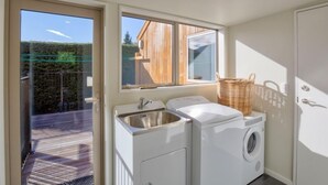 A laundry area with a washing machine, a dryer, and a sink. - 5 Bedroom Queenstown Lakefront Home (Kelvin Heights)
