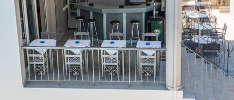 A bar area with tables and stools, a counter, and a staircase leading to an outdoor seating area.