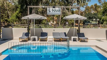 Alberca al aire libre, sombrillas en la alberca y camastros