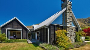Una casa moderna con una chimenea de piedra, ventanas amplias y un jardín cuidado.