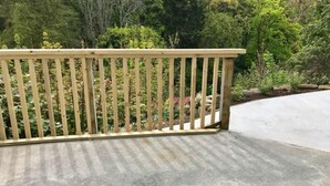 Una terraza de madera con suelo de hormigón, rodeada de abundante vegetación y árboles.