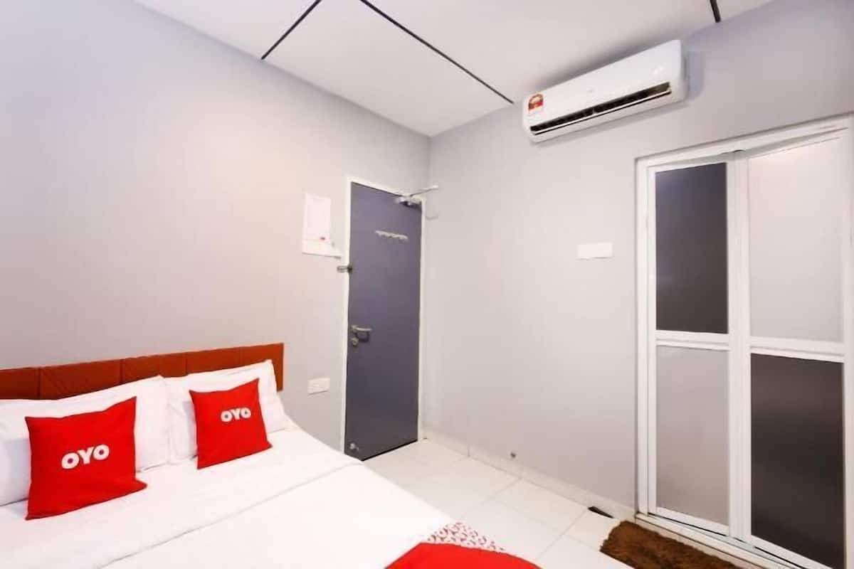 Quarto de hotel com cama, porta, ar condicionado e janela.