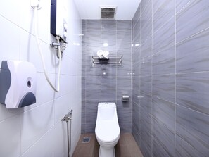 A modern bathroom with a toilet, a hand dryer, and a shower head.