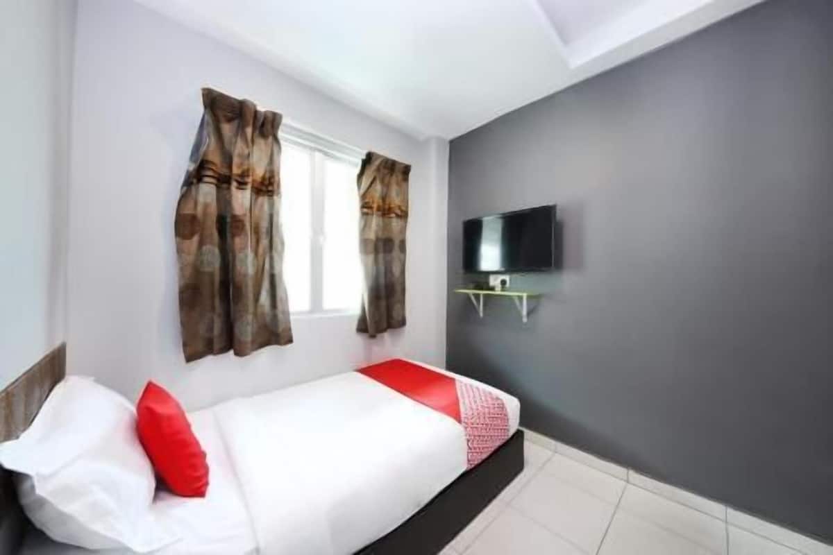 Quarto com cama, cortinas, televisão na parede e janela.