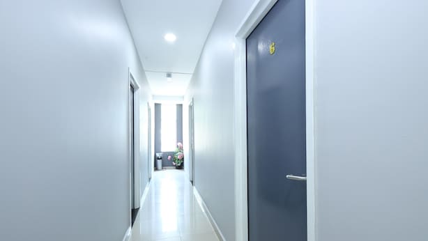A clean, modern hallway with a blue door on the right and a trash bin in the center.