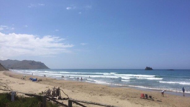 Una playa con tiendas de campaña y gente.