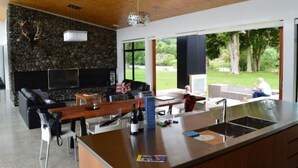 A modern living room with a stone wall, a fireplace, and a view of a garden.