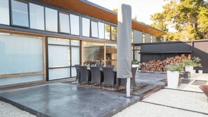 A modern outdoor dining area with a concrete floor, a covered table, and chairs.