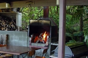 Enjoy meals and conversations in a tranquil outdoor setting with a traditional stove and comfortable seating.